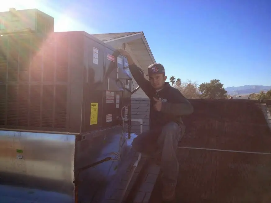 HVAC technician performing AC Tune-Up on a rooftop unit in White City